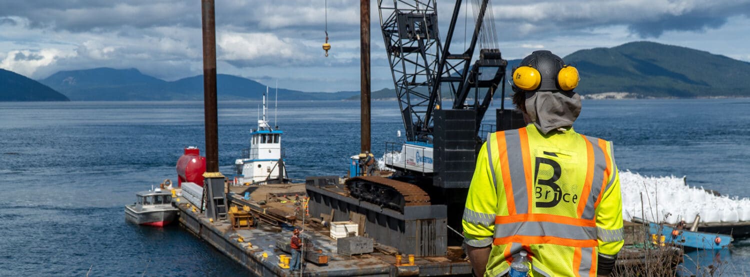 Man looking at large landing craft boat carrying a crane