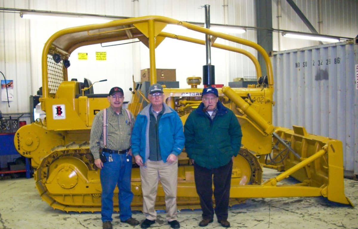 Three men standing in front of a dozer