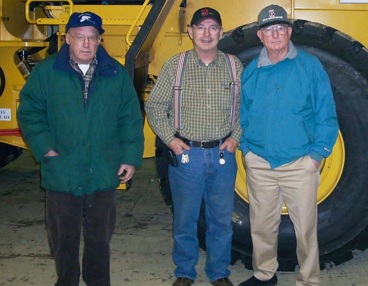 Three men standing in front of a tractor